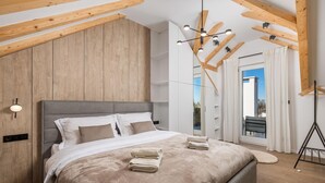 A modern bedroom with a large bed, wooden ceiling beams, and a view of the outdoors. - Cozy home in Skrip with WiFi (Skrip)