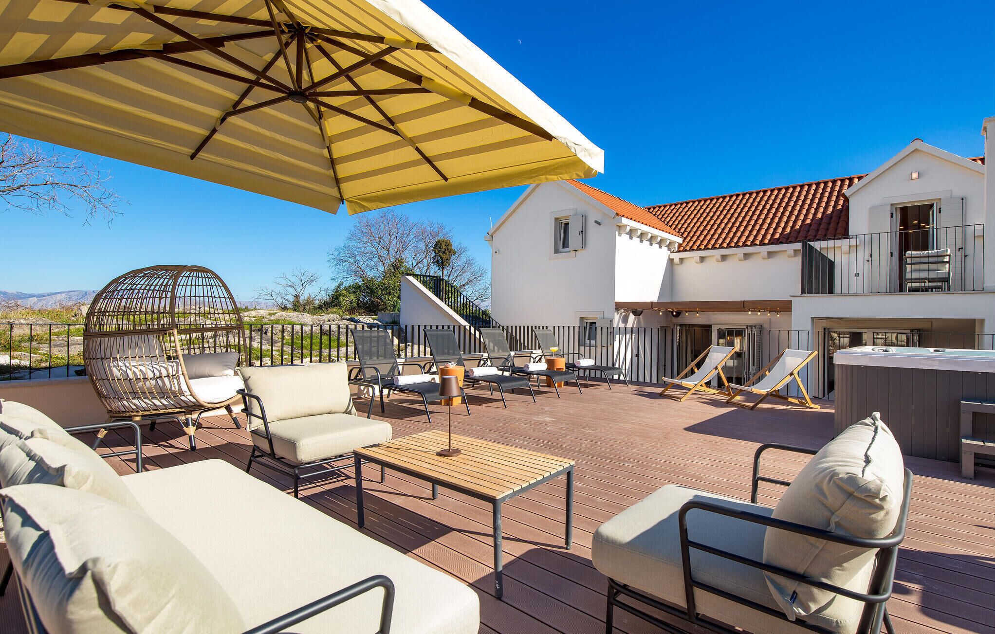 An outdoor patio area with lounge chairs, a table, and a large umbrella.