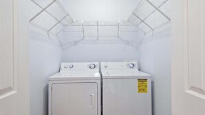 Una lavandería con dos secadoras blancas y estantes metálicos para tender ropa.