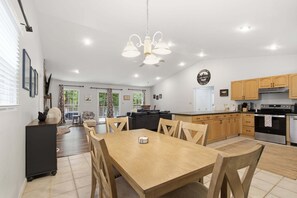 A spacious kitchen with wooden cabinets, a dining table, and a ceiling fan.
