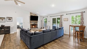 A modern living room with a large sectional sofa, a fireplace, and a dining area with a table and chairs.