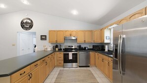 Una cocina moderna con armarios de madera, electrodomésticos de acero inoxidable y encimera negra.
