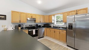 A modern kitchen with wooden cabinets, stainless steel appliances, and a large refrigerator.