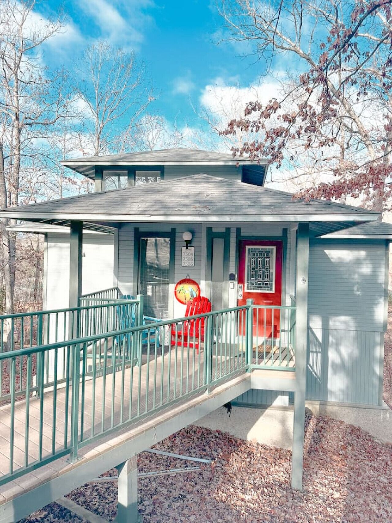 A small, single-story building with a red door and a small porch area.