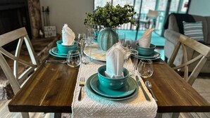 A dining table set with teal plates, glasses, and a vase with greenery.