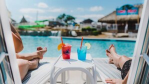 A poolside view with lounge chairs and drinks.