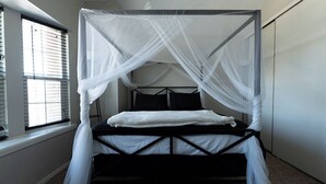 Un letto singolo con baldacchino, una finestra con persiane e un pavimento coperto di moquette.