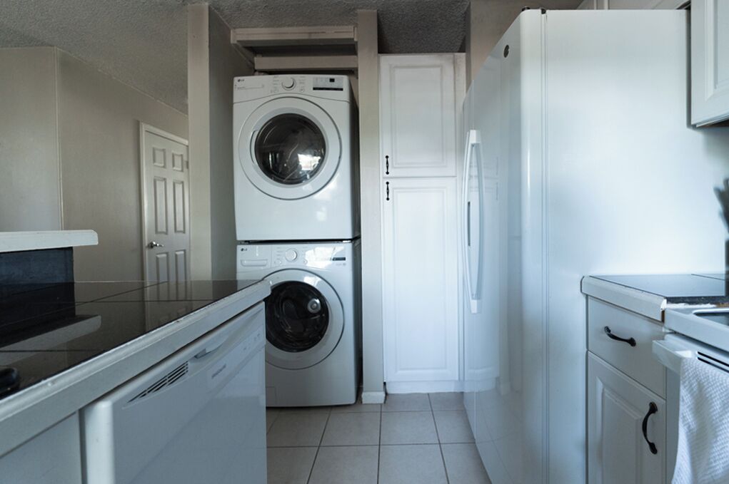 Una cocina compacta equipada con lavadora, refrigerador y microondas.