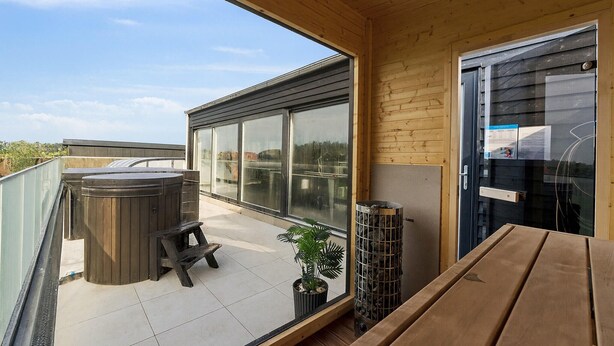 A balcony with a hot tub, a wooden bench, and a potted plant. - Stunning home in Spøttrup with sauna (Spøttrup)