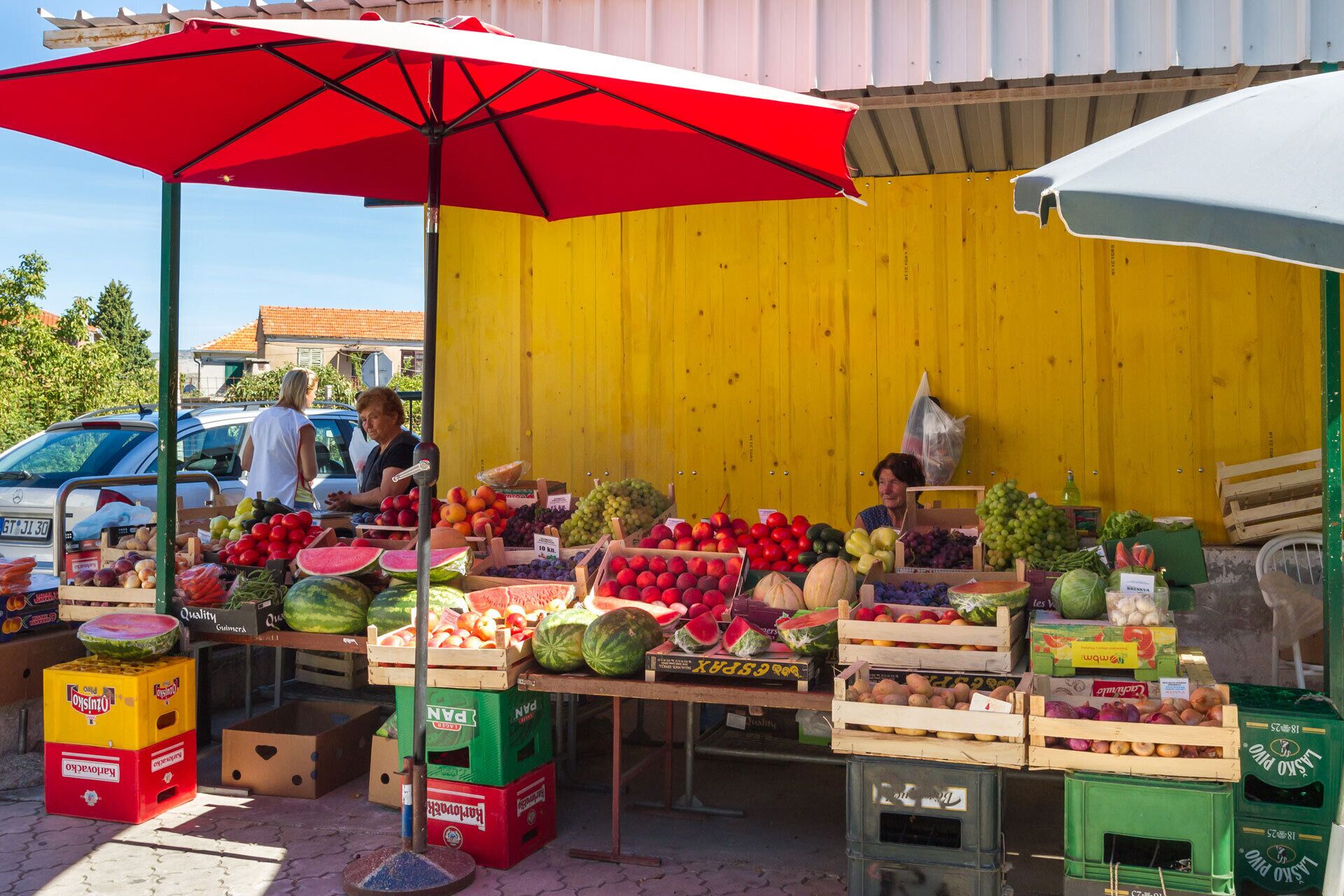 A fruit stand with various fruits and vegetables displayed in crates and boxes.