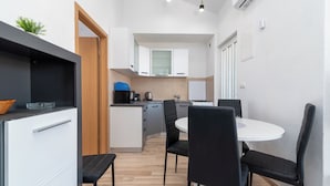 Una cocina compacta con armarios blancos, una mesa de comedor con cuatro sillas y una pequeña isla con un lavamanos.