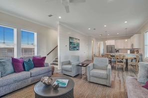 A spacious living area with a sofa, armchairs, a coffee table, and a dining area with a table and chairs. - Azure Horizon Beachfront Charm in Gulf Shores (Gulf Shores)
