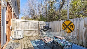 A backyard with a patio, outdoor furniture, a grill, and a railroad crossing sign.