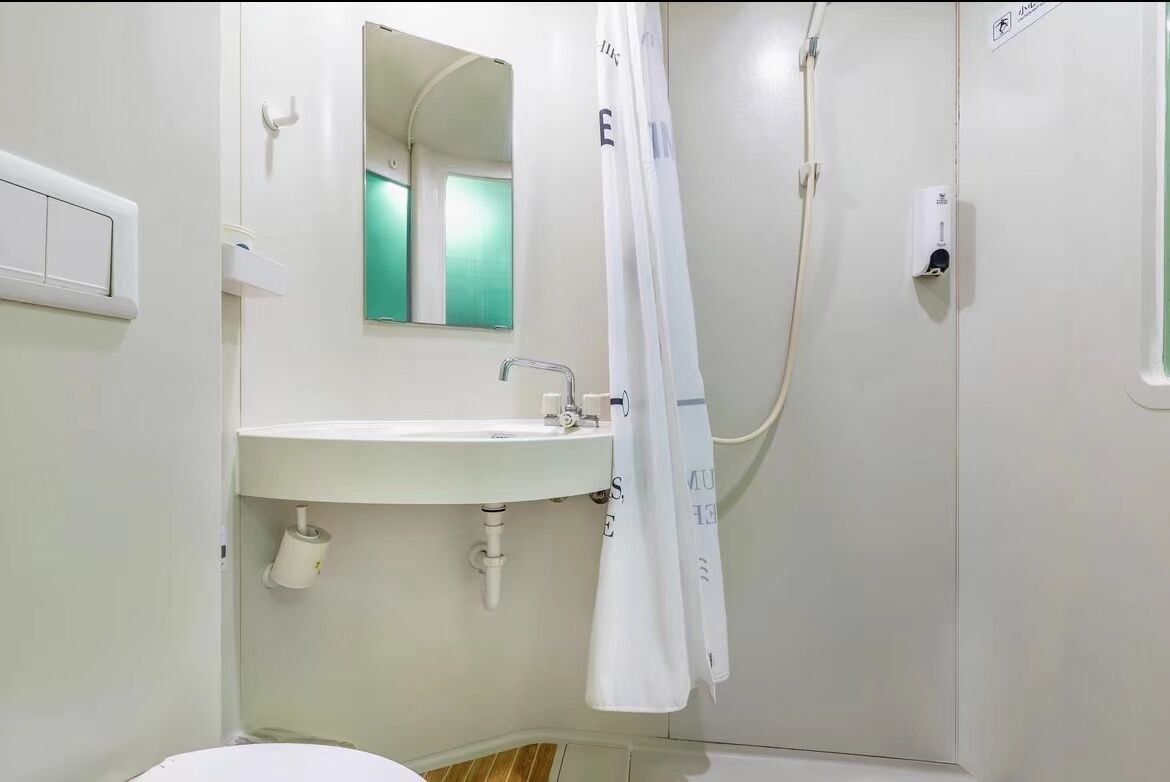 Une salle de bain avec un lavabo blanc, un miroir et un rideau de douche.