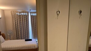 Una camera da letto con un letto, un comodino, una ventola e una finestra con tende.