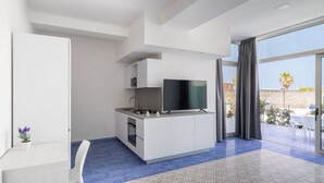 Een moderne keuken met een flatscreen televisie, witte kasten en een blauwe betegelde vloer.