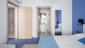 Een moderne hotelkamer met een groot bed, een badkamer met douche en een kitchenette.