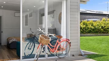 A red bicycle with a basket parked outside a house with a glass door.