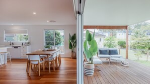 A modern kitchen with white cabinetry and a wooden dining table. - Seaglass Beach House - Beautifully designed retreat in the heart of Narrawallee (Narrawallee)