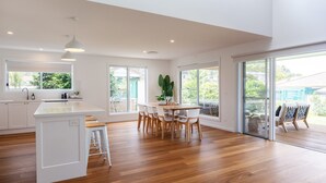 A spacious kitchen with a central island, large windows, and a sliding glass door leading to a balcony. - Seaglass Beach House - Beautifully designed retreat in the heart of Narrawallee (Narrawallee)