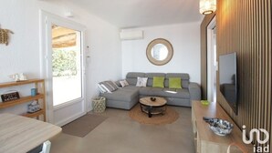 A modern living room with a grey sofa, a round coffee table, and a television on a wooden wall. - Villa Anza de la Olla - Le Racou plage - 13 people - 5 bedrooms (Argelès-sur-Mer)