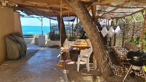 An outdoor patio with a wooden table and chairs, a swing, a grill, and a view of the sea. - Villa Anza de la Olla - Le Racou plage - 13 people - 5 bedrooms (Argelès-sur-Mer)
