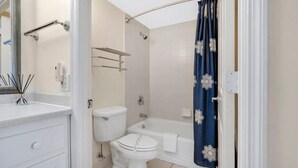 Een badkamer met toilet, bad en douchegordijn.