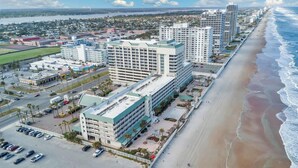 A coastal hotel with multiple buildings, a parking lot, and a beach view. - Beachfront studio w/ direct Atlantic views (Daytona Beach)