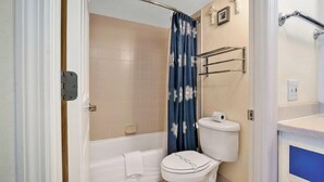 A bathroom with a bathtub, toilet, and shower curtain. - Beachfront studio w/ direct Atlantic views (Daytona Beach)