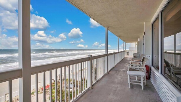 A balcony with a view of the ocean, white railings, and several chairs. - Beachfront studio w/ direct Atlantic views (Daytona Beach)