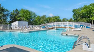 A swimming pool with multiple lanes, a white fence, and lounge chairs.