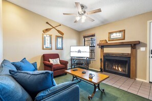 A living room with a fireplace, a ceiling fan, and a framed picture on the wall.