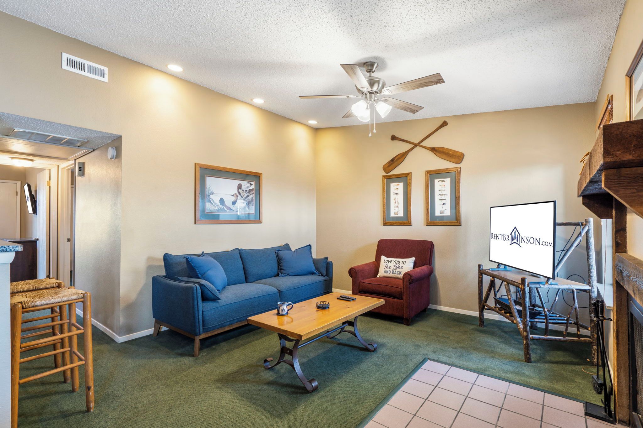 A living room with a blue sofa, a wooden coffee table, a red armchair, and a ceiling fan.