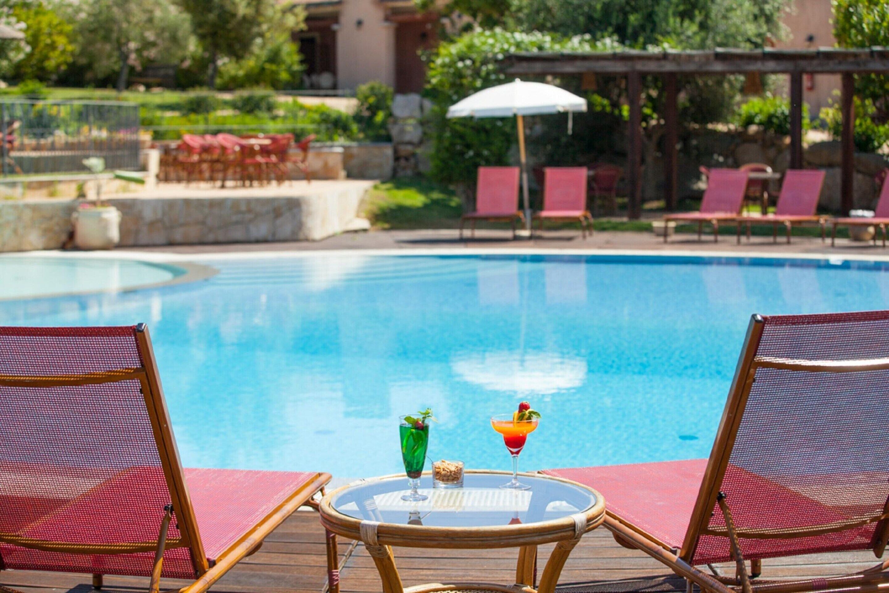 A poolside area with lounge chairs and a table with drinks.