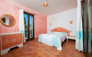 Un dormitorio con cama, cómoda, espejo y puerta corrediza de vidrio que da a un balcón.