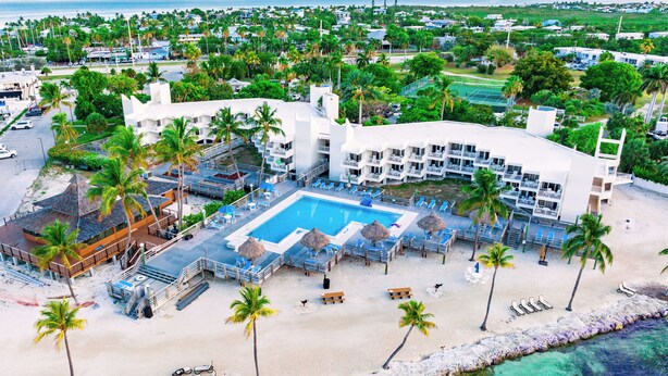 Un resort con piscina amplia, playa y vistas al océano.