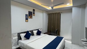 Ein modernes Hotelzimmer mit einem großen Bett, einem Deckenventilator, eingelassener Beleuchtung und einem Marmorboden.