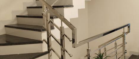 A modern staircase with metal railings and black marble steps.