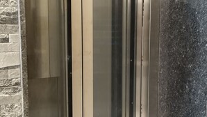 Ein moderner Aufzug mit Glastüren und metallischem Innenraum.