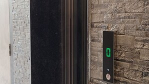 Ein Aufzug mit digitaler Anzeige, die '0' zeigt, und einem Notrufschalter darüber.