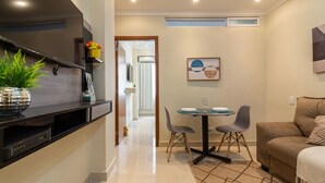 A modern kitchen with a built-in oven, a dining area with a table and chairs, and a living area with a sofa and a TV. - Cosy in Copacabana 7 minutes from the beach | FM211 (Rio de Janeiro)