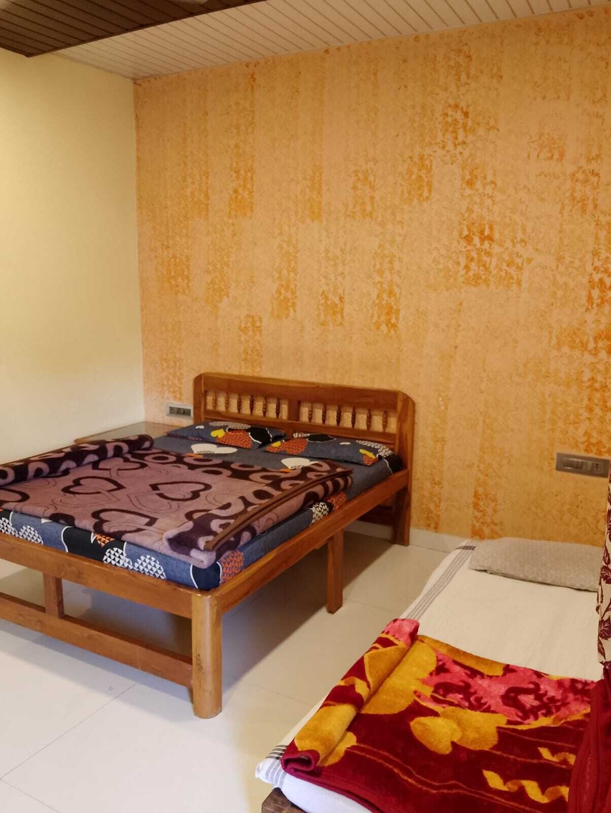 A single bed with a wooden frame and patterned bedding, a bedside table, and a wall with a textured finish.