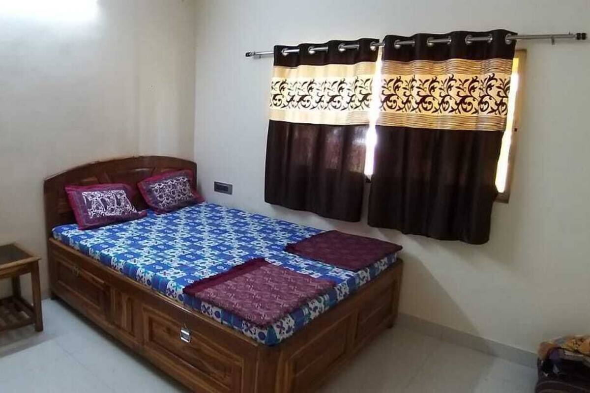 Ein Schlafzimmer mit einem hölzernen Bett, einem kleinen Holztisch und einem Vorhang mit einem gemusterten Design.