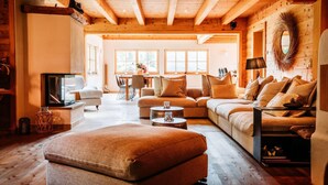 A cozy living room with a wooden ceiling, a sofa set, a television, and a fireplace. - Chalet in Tyrol Near Ski-area (Waidring)