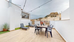 Eine Dachterrasse mit Esstisch, Stühlen und einem Blumentopf.