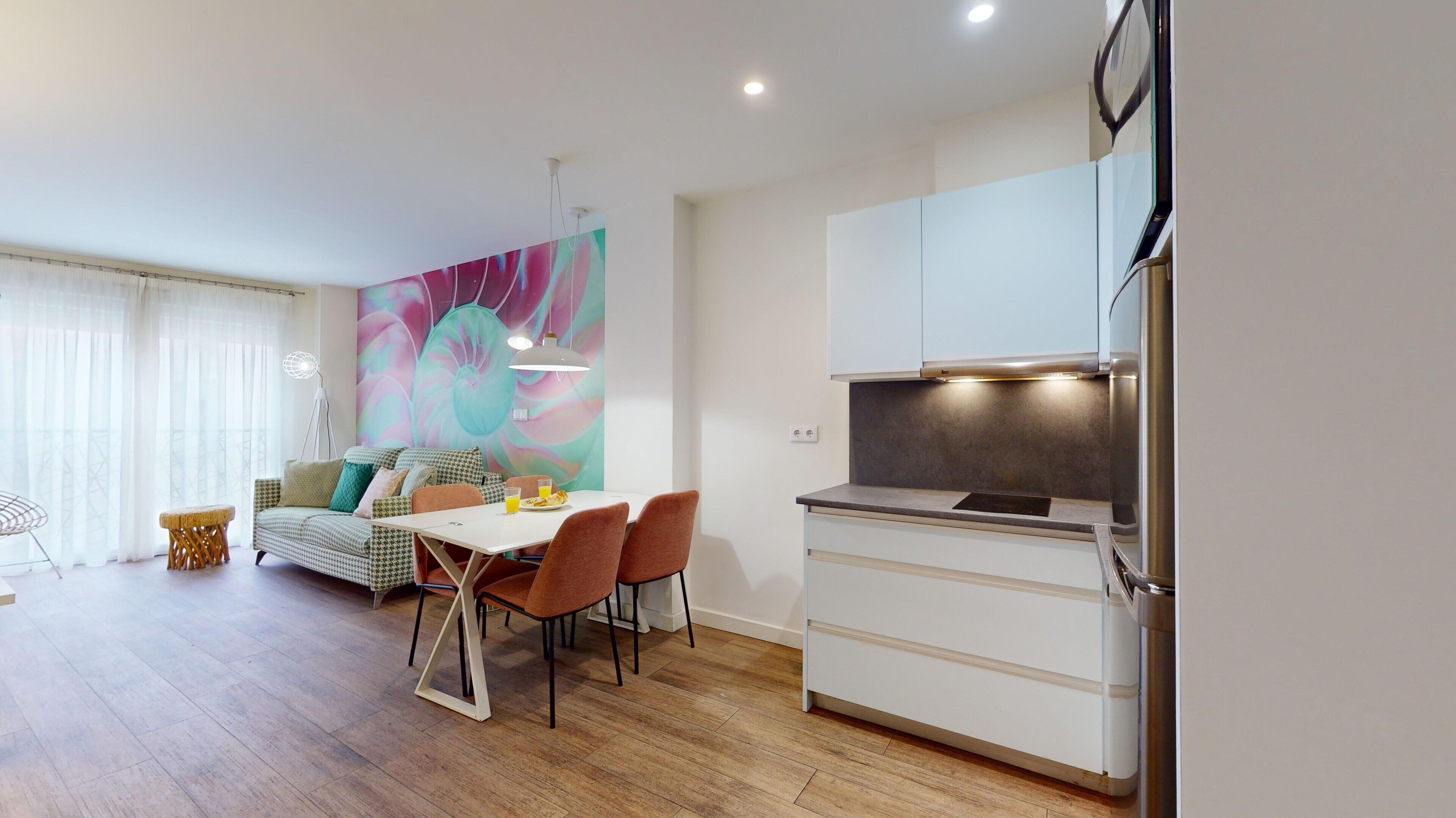 A modern apartment with a dining area, kitchen, and living space.