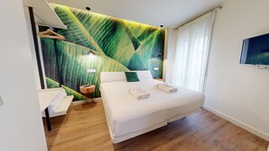 Ein Hotelzimmer mit einem Bett, einem Nachttisch aus Holz, einem an der Wand montierten Fernseher und einem großen Fenster mit Vorhängen.