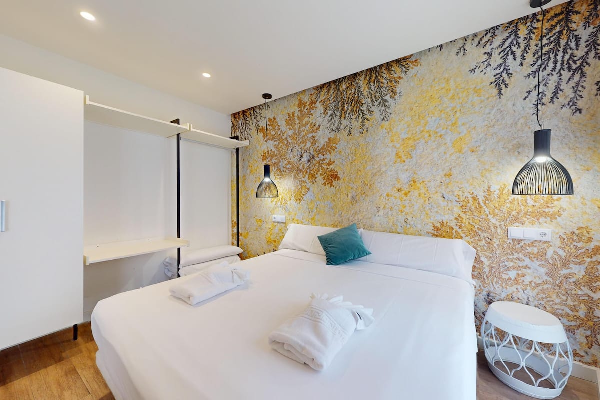 Un dormitorio con cama, armario blanco y un detalle decorativo en la pared.