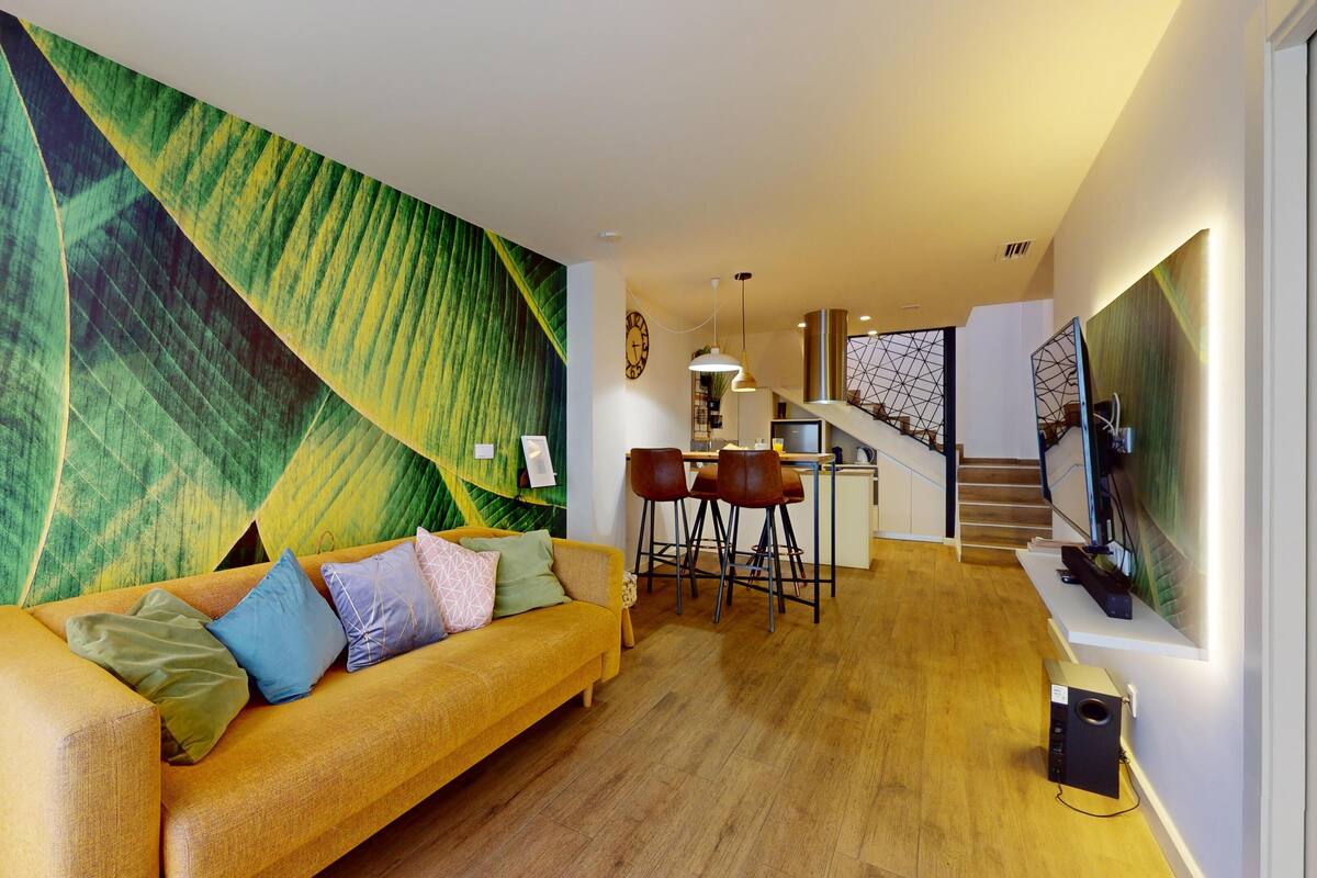 Una sala de estar moderna con un sofá, una zona de comedor y una escalera.