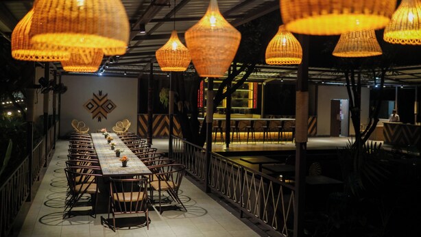 A long dining table with chairs, surrounded by hanging wicker lamps. - Tiki Farms – Polynesian Boutique Resort, Karjat (Karjat)